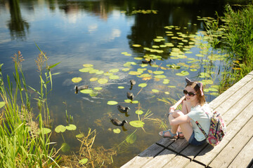 Cute young girl sitting on a pier by Pastovis lake in Moletai town, one of the oldest settlements...