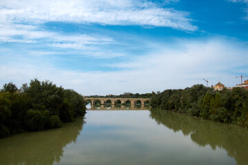Fototapeta na wymiar El viejo puente junto al río, con cielo nublado