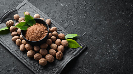 Ground nutmeg in bowl on black stone background. Fragrant Indian spices. Free space for your text. Top view.
