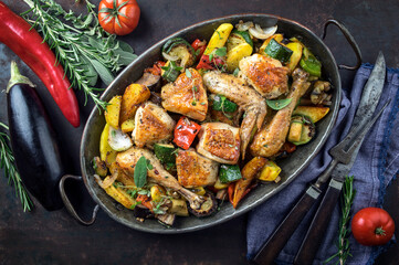 Traditional Mediterranean roasted chicken with fried  vegetable offered as top view in a rustic casserolle