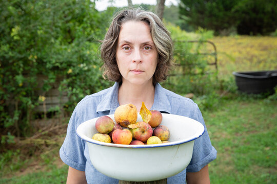 woman in chambray shirt with bowl of apples