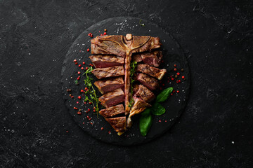 Juicy grilled steak from Angus with spices and herbs on a black background. Bull Angus. Top view....