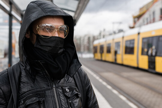 Man wearing black medical mask and goggles outside