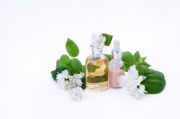 Essential oil and cream with jasmine flower. Aromatherapy and alternative medicine. Jasmine tincture in a glass jar and a lot of fresh buds. Soft focus, photo light colors. Copy space