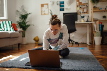 Woman Using Laptop On The Floor Of Her Home