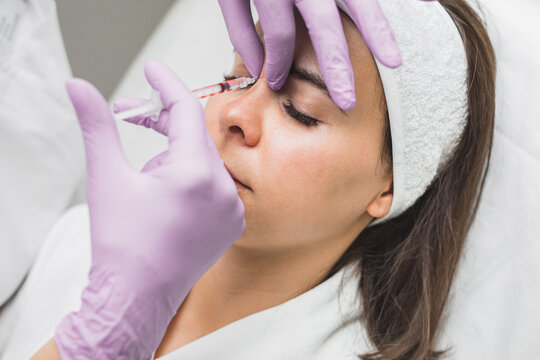Close up of beautician expert's hands injecting botox in female forehead