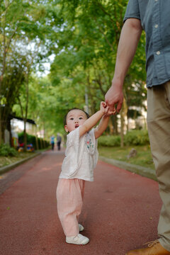 Babygirl walking with dad in the park