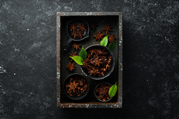 Anise stars in bowls on black stone background. Badian - Indian spices. Top view.