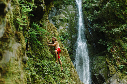 Young Man exploring a waterfall and rockclimbing