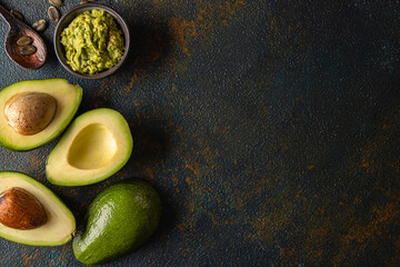 avocado and guacamole on a dark rustic background top view with copy space for your text.