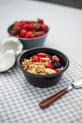 Healthy breakfast Granola with strawberries, banana, nuts and blackberries stands on the table. Ingredients in the background.
