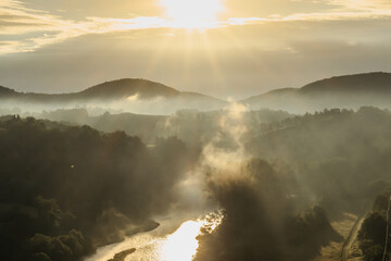 Panoramic view of a river and misty forest. Foggy morning outdoors.Misty forest scenery.Colorful summer morning with golden sunlight.Fantastic foggy sunrise.Beautiful sun rays with clouds.