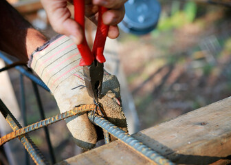 Attaching the rebars to each other. Worker's hands fasten the reinforcement with wire. Close up, selective focus.
