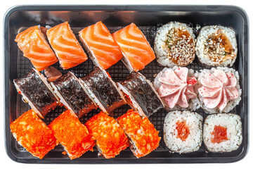 assorted japanese rolls in a black plastic box isolated on white..