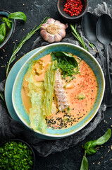 Seafood soup. Creamy tuna soup in a bowl on a black stone background. Top view. Rustic style.