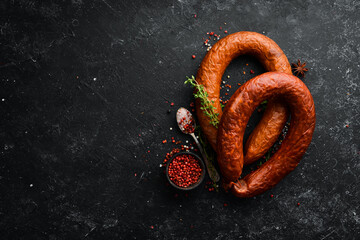 Fresh baked sausage. Salami on a black stone background. Top view. Free space for text.