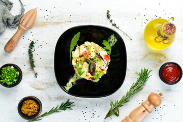 Vegetable salad with chicken, egg and mayonnaise sauce on a black plate. Top view. Free space for your text.