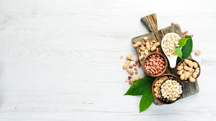 Peanuts in bowls on white wooden background. Nut background. Top view.