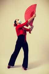 woman dancing flamenco sevillanas with fan and mask