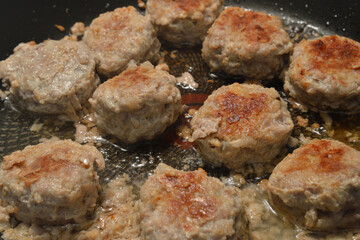 Meat cutlets are fried in frying pan.