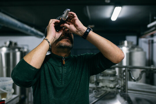 Brewer examining beer in refractometer