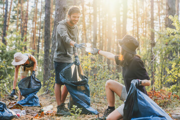 Boy and girl with friends picking up plastic trash from forest. Ecoway concept