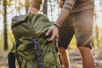 Fototapeta Close up of male hiker holding his camping backpack. Traveler opening backpack while traveling in beautiful wood obraz