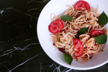 Pasta, spaghetti with tomato sauce in black bowl on marble background