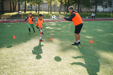 Young soccer coach instructs teen players. A young professional coach trains the ball kicks with young football players.