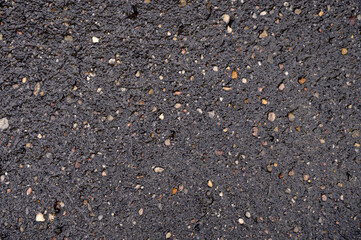 Abstract background of black wet asphalt with inclusions of pebbles