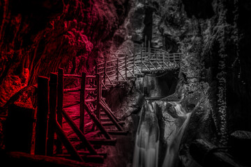 Red light and tilt shift effect of stalactites above the walkway in caves carved out of sandstone,...