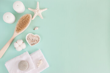 Natural body brush with bristles, white starfish, sea salt for the bath and a white wax candle and a pair of towels.