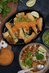 Fried vegan tamales in cast iron serving plate along with ranchero sauce and chili cilantrio salsa
