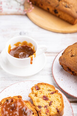 Homemade cake with raisins, almonds, soft caramel and a cup of coffee on a white wooden background. Side view, selective focus.