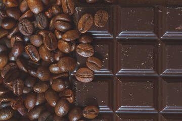 Coffee beans over chocolate bar, top view, food background, tinted