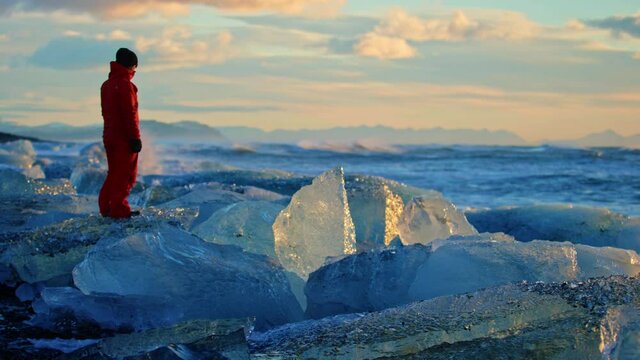 Slow motion, man stands on icebergs in Okulsarlon Beach