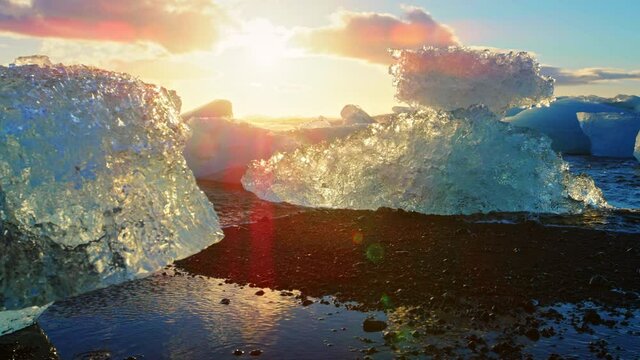 Sun shines over icebergs on Okulsarlon Beach, slow motion close up
