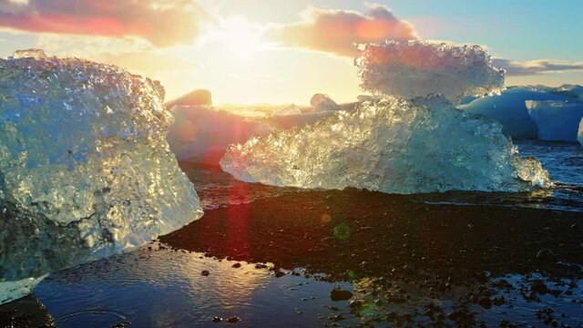 Sunlight reflects off icebergs on Okulsarlon Beach, slow motion close up