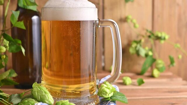 Beer. Cold Craft light Beer in a glass with water drops. Pint of Beer close up on a wooden background. Beer is pouring from the bottle. Border design. High quality 4k footage