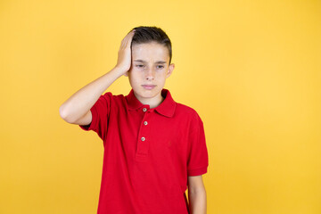 Young beautiful child boy over isolated yellow background putting one hand on her head smiling like she had forgotten something