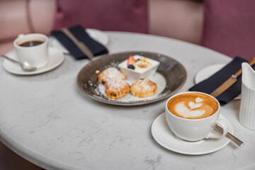 Coffee art and scones on the table for afternoon tea