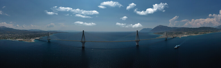 Obraz premium Aerial drone photo of world famous cable suspension bridge of Rio - Antirio Harilaos Trikoupis, crossing Corinthian Gulf, mainland Greece to Peloponnese, Patras