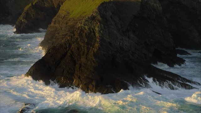 Panning aerial, waves crash over Ireland coastline