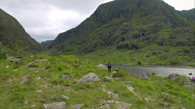 Pan right aerial, woman hikes in Ireland mountains