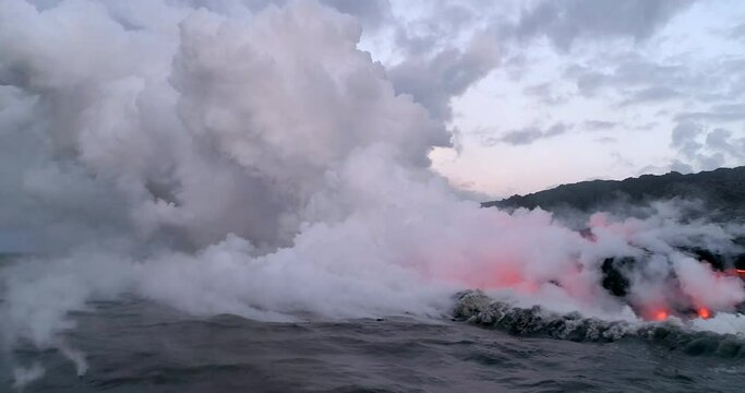 Waves crash over lava flow along coastline, aerial