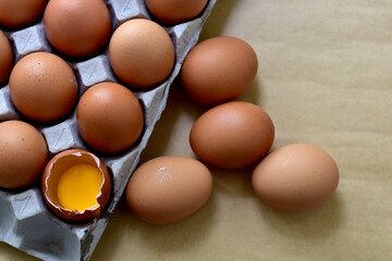 Brown eggs in carton box. Broken egg with yolk, Easter eggs In Paper Container, selective focus points.