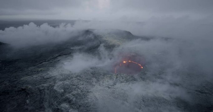 Wide pan right aerial, smoke rises from active volcano