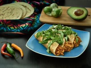 traditional plate of mexican food golden tacos with chicken with lettuce