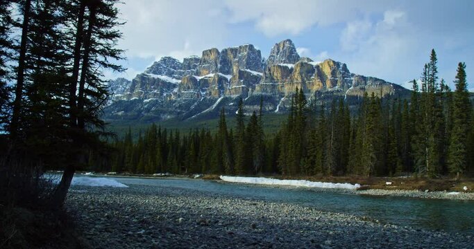 Low angle, mountain towers over river in Banff National Park
