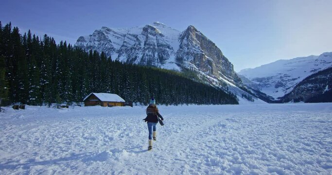 Lone woman runs over frozen lake in Banff National Park, tracking shot